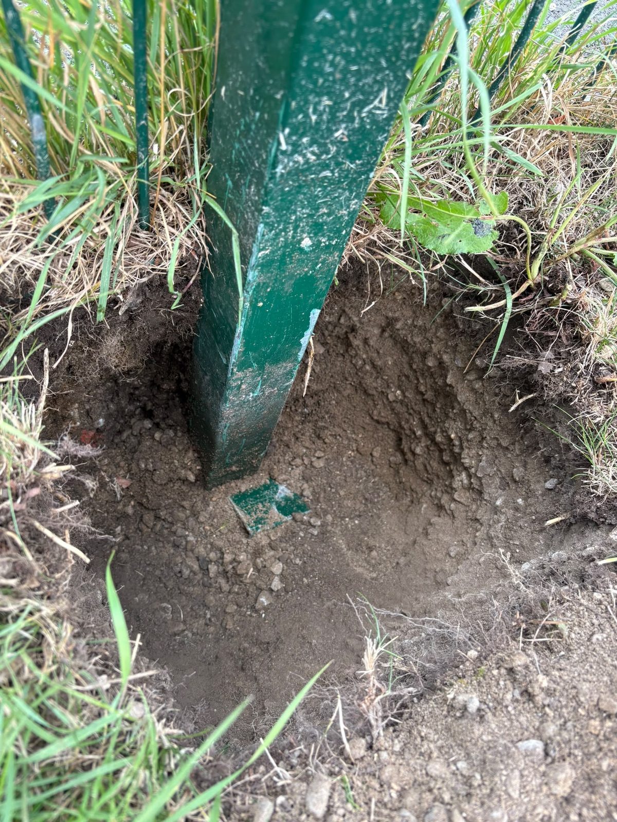 Fence post excavated to reveal a shallow base with almost no concrete, the cause of the movement